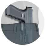 Black handgun holstered inside the waistband of blue pants.