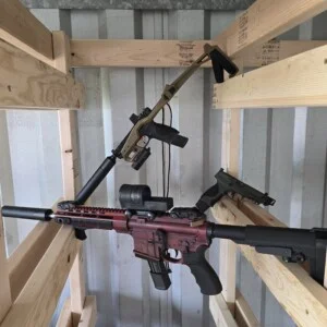 Guns are displayed on wooden racks in a storage area.