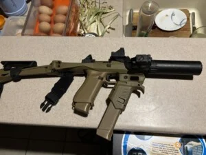 A tactical rifle with attachments is displayed on a kitchen counter.