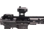 A tactical rifle with a mounted sight and safety selector switch visible.