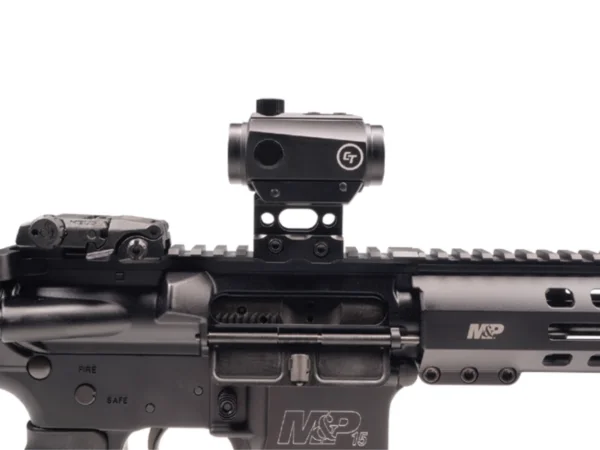 A tactical rifle with a mounted sight and safety selector switch visible.