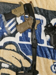 A handgun and accessories placed on a patterned blanket.