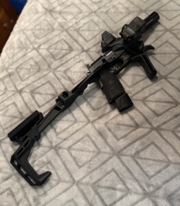 A black tactical firearm with attachments on a patterned blanket.