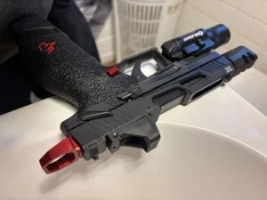 A black handgun with red accents and a mounted flashlight.