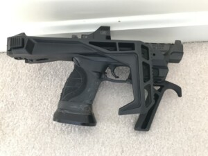 A black handgun with a custom frame kit on a light carpeted floor.