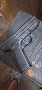 A black handgun placed on a textured surface.
