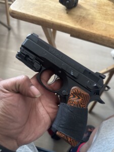Person holding a CZ 75 P-01 pistol with an orange patterned grip.