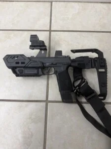 A black airsoft gun with a mounted sight on a tile floor.