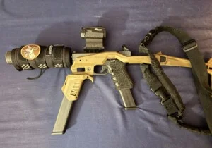 A tactical gun with attachments and a patch, resting on a blue fabric surface.
